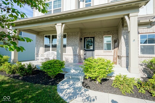 entrance to property with a porch and brick siding