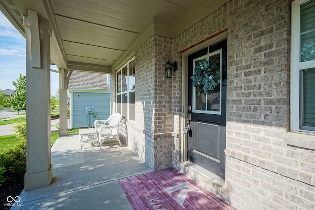 doorway to property with a porch and brick siding