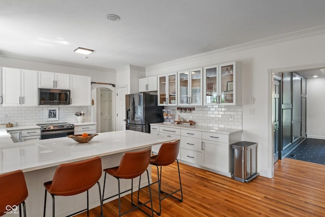 4601 Fairhope Dr, Indianapolis, IN 46237 - kitchen featuring stainless steel appliances, a kitchen breakfast bar, decorative backsplash, white cabinets, and crown molding