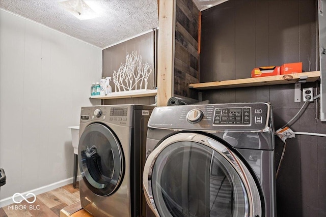 laundry area with independent washer and dryer, a textured ceiling, and wood finished floors