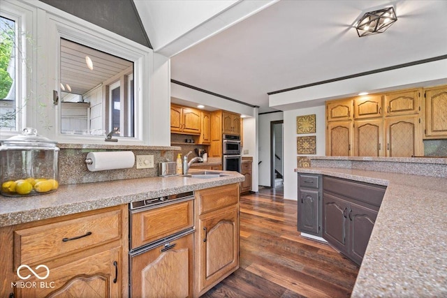 kitchen with a sink, backsplash, stainless steel double oven, dark wood-type flooring, and light countertops