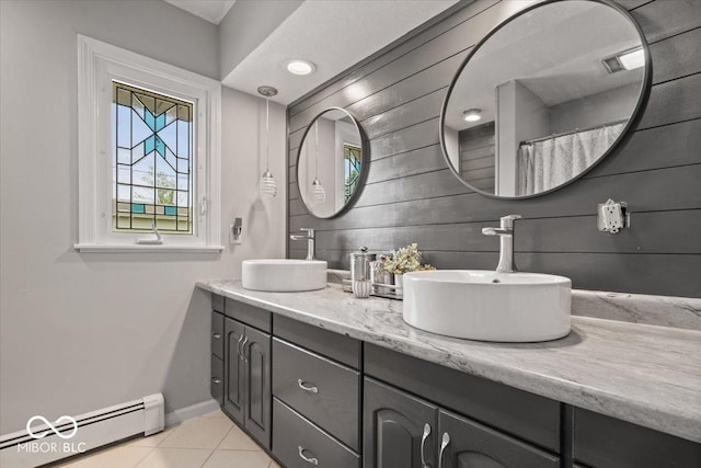 bathroom featuring a baseboard radiator, tile patterned floors, baseboards, and double vanity