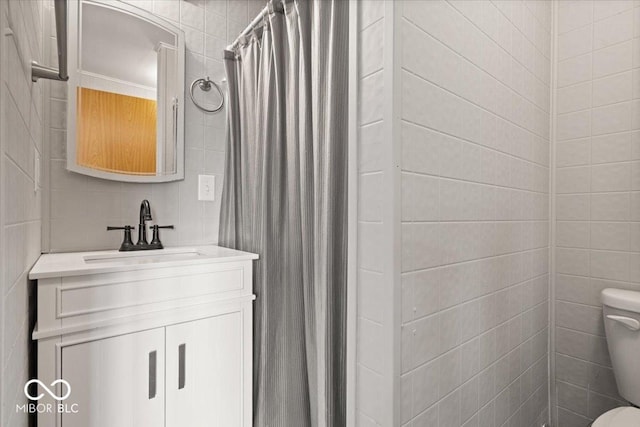 bathroom with tile walls, toilet, vanity, and a shower with curtain