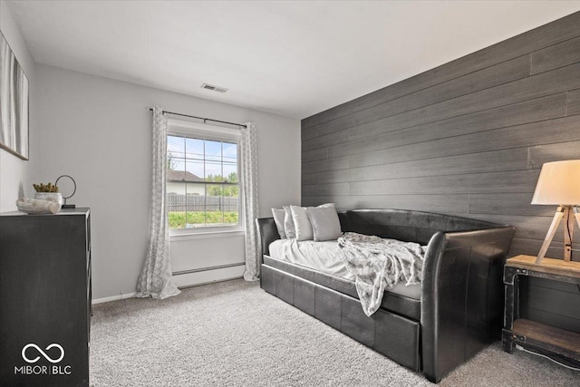 bedroom with a baseboard radiator, carpet flooring, wood walls, and baseboards