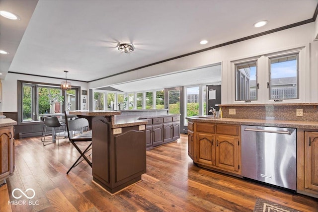 kitchen with dishwasher, ornamental molding, a kitchen breakfast bar, dark wood-style floors, and healthy amount of natural light