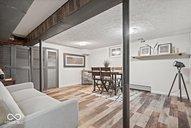 living room featuring baseboards, wood finished floors, a baseboard radiator, and a textured ceiling