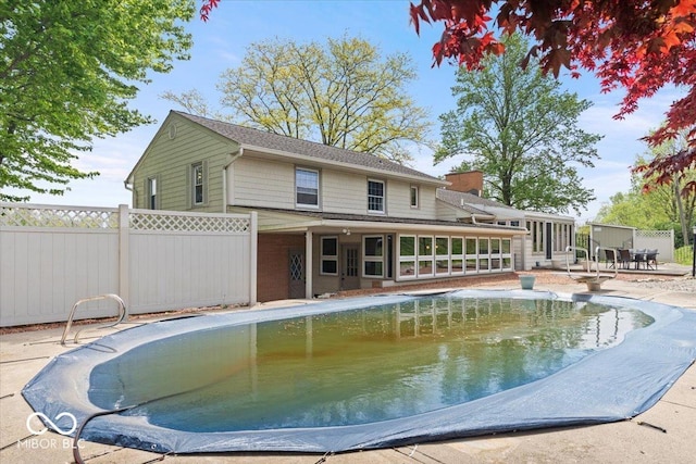 view of swimming pool with fence, a patio area, and a diving board