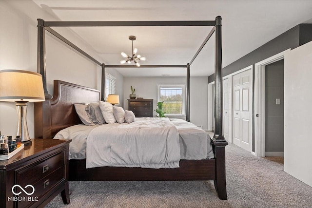 carpeted bedroom featuring a chandelier and two closets
