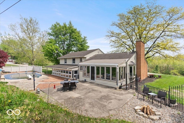 back of property featuring an outdoor fire pit, a chimney, a fenced backyard, and a patio area