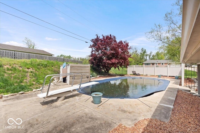 view of swimming pool featuring a fenced backyard, a diving board, and a patio area