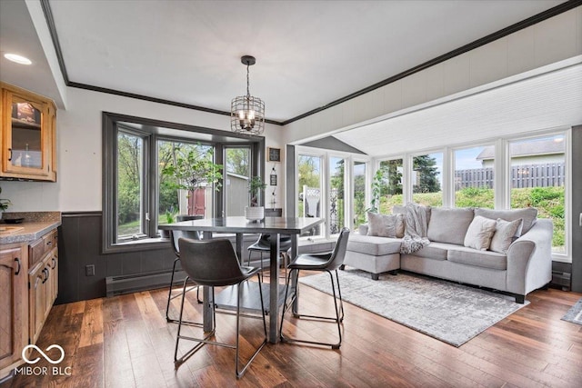 dining area featuring a baseboard heating unit, dark wood finished floors, ornamental molding, wainscoting, and a chandelier