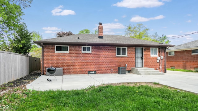 rear view of house with fence, a chimney, a patio, and brick siding