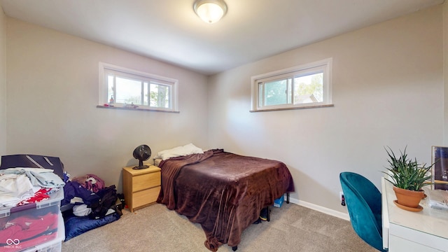 bedroom with multiple windows, light colored carpet, and baseboards