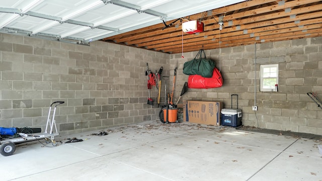 garage featuring concrete block wall and a garage door opener