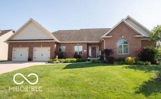 view of front of property featuring brick siding, concrete driveway, a front lawn, and a garage