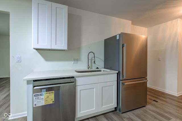 4956 W 11th St, Speedway, IN 46224 - kitchen with appliances with stainless steel finishes, a sink, white cabinetry, light wood-type flooring, and light countertops