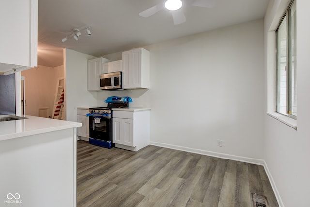 4956 W 11th St, Speedway, IN 46224 - kitchen featuring stainless steel appliances, light wood-style flooring, a ceiling fan, and white cabinets