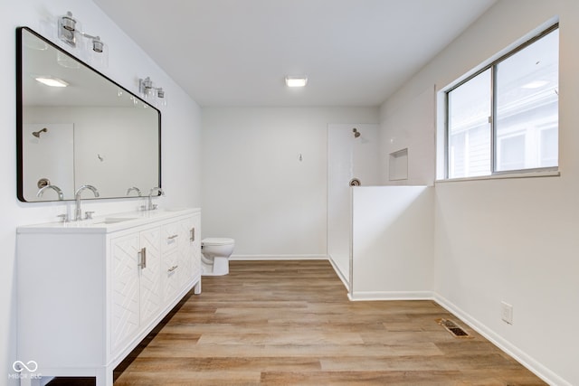 4956 W 11th St, Speedway, IN 46224 - full bathroom featuring double vanity, toilet, a shower, wood finished floors, and baseboards