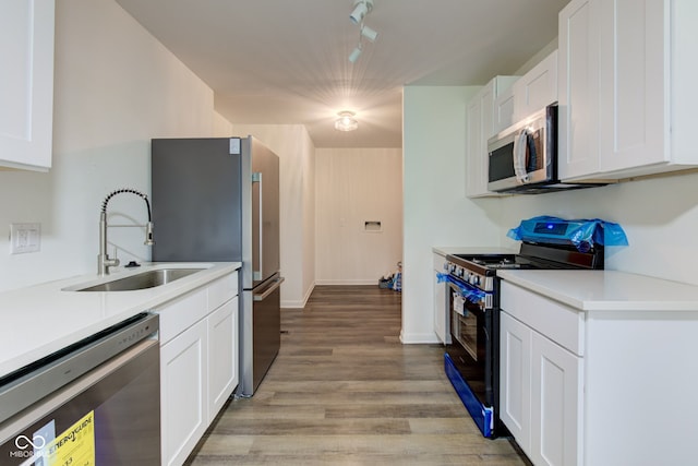 4956 W 11th St, Speedway, IN 46224 - kitchen with stainless steel appliances, a sink, white cabinets, light wood-style flooring, and light countertops