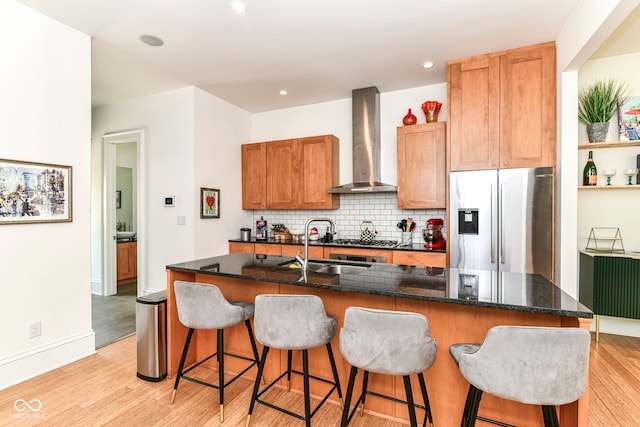 1630 N New Jersey St, Indianapolis, IN 46202 - kitchen with stainless steel appliances, wall chimney exhaust hood, backsplash, light wood finished floors, and a kitchen island with sink