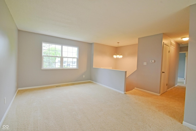 carpeted spare room featuring a chandelier and baseboards
