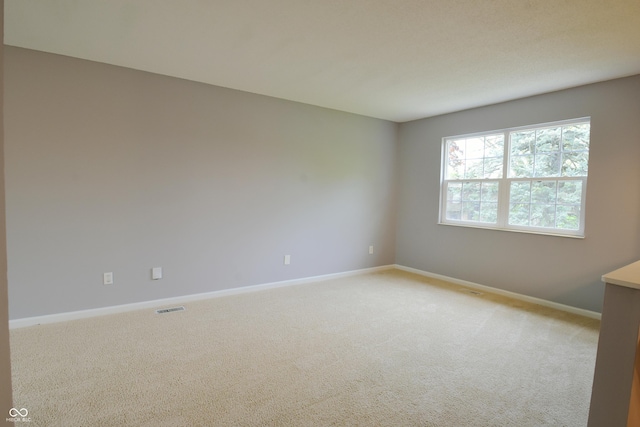 unfurnished room featuring baseboards and light colored carpet