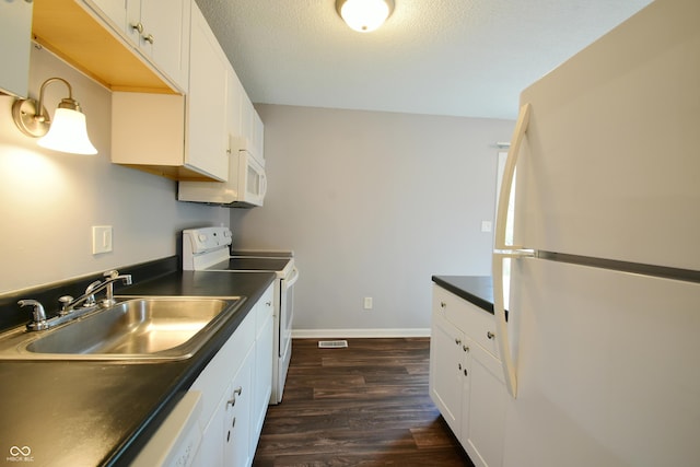 kitchen featuring white appliances, a sink, dark countertops, dark wood-style flooring, and baseboards