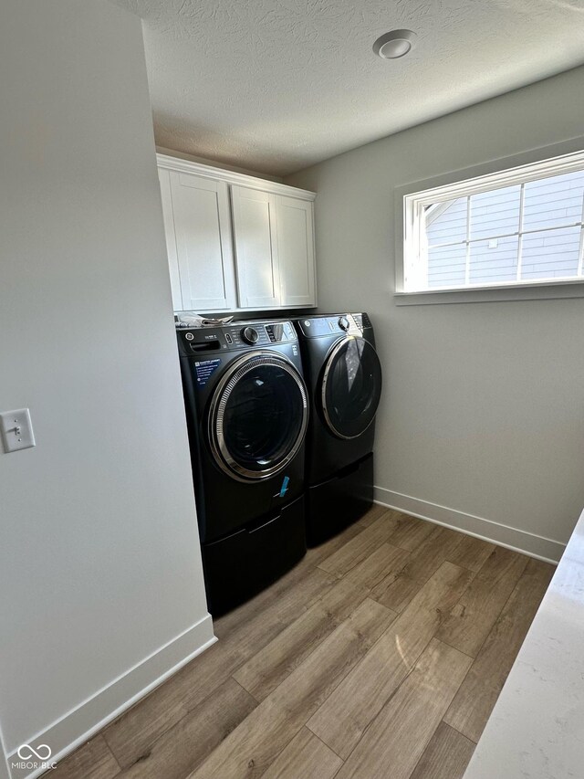 1679 W 171st St, Westfield, IN 46074 - laundry area featuring separate washer and dryer, light wood finished floors, baseboards, cabinet space, and a textured ceiling
