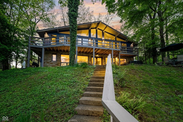 7753 Ivy Dr, Nineveh, IN 46164 - back of house at dusk with stairs, a deck, and stone siding