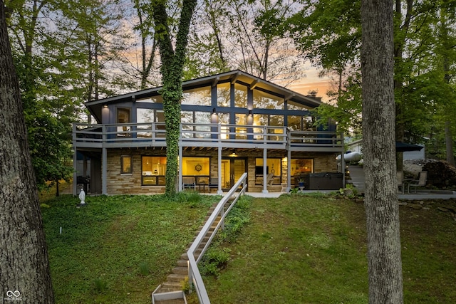 7753 Ivy Dr, Nineveh, IN 46164 - back of property at dusk featuring a hot tub, stone siding, a lawn, and a wooden deck
