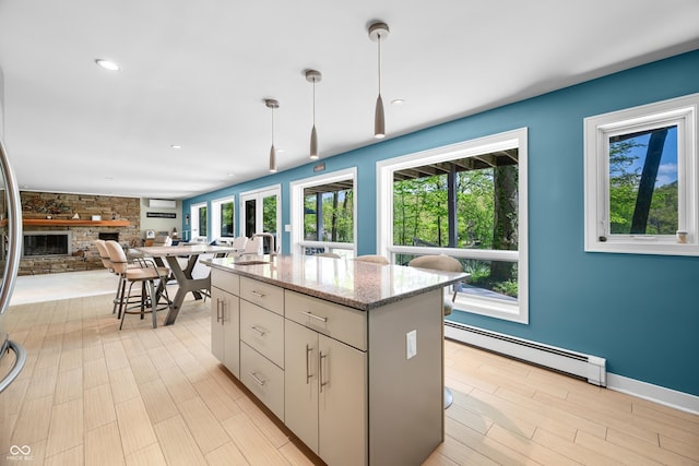 7753 Ivy Dr, Nineveh, IN 46164 - kitchen with baseboard heating, a stone fireplace, a sink, a center island with sink, and open floor plan