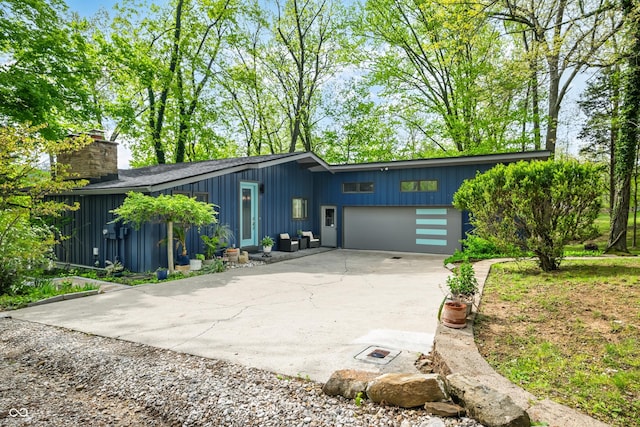 7753 Ivy Dr, Nineveh, IN 46164 - view of front of home featuring concrete driveway, an attached garage, a chimney, and board and batten siding