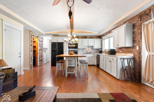 kitchen featuring dishwasher, black fridge with ice dispenser, a sink, a kitchen bar, and a center island