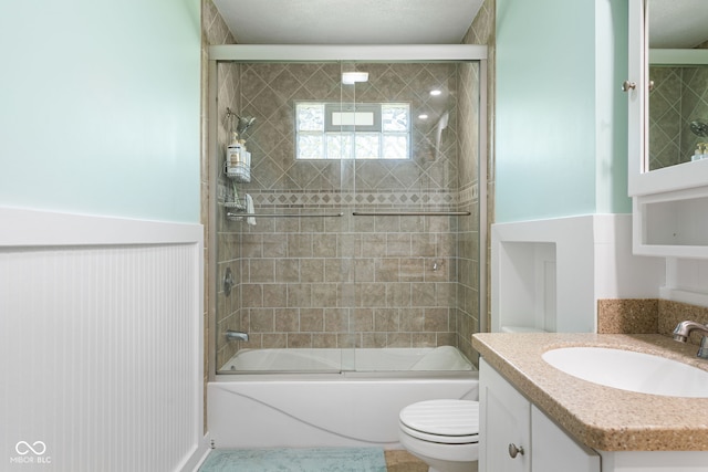 full bathroom with vanity, enclosed tub / shower combo, toilet, and wainscoting