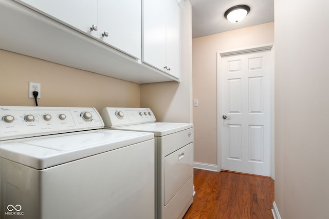 washroom with cabinet space, wood finished floors, washer and dryer, and baseboards