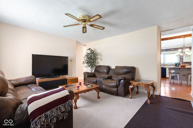 living room featuring ceiling fan, a chandelier, and baseboards