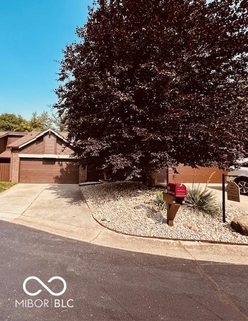 209 Brighton Ct, Greenwood, IN 46143 - view of property hidden behind natural elements with concrete driveway and a garage