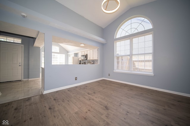 empty room featuring lofted ceiling, plenty of natural light, dark wood-style flooring, baseboards, and a smoke detector