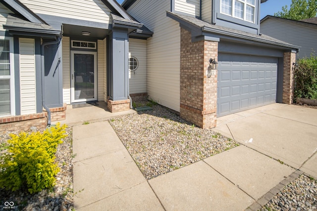 property entrance featuring brick siding, a garage, and concrete driveway