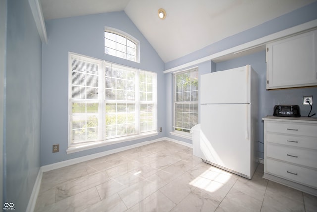 unfurnished dining area with light marble finish floors, baseboards, and high vaulted ceiling