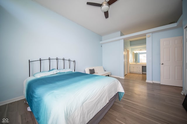 bedroom with wood finished floors, baseboards, connected bathroom, and vaulted ceiling