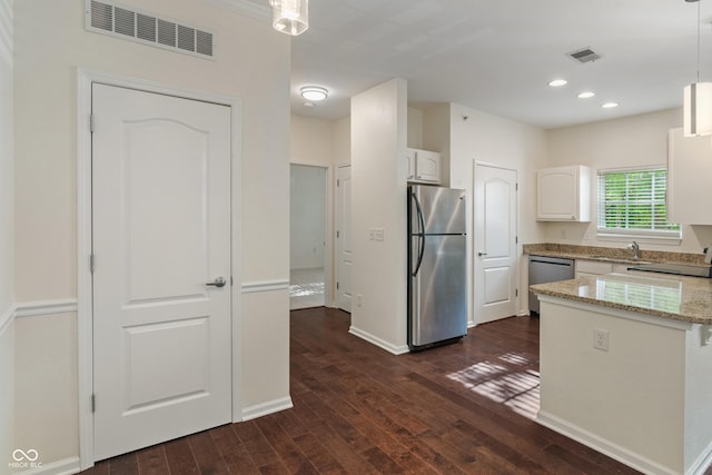 kitchen featuring stainless steel appliances, dark wood-style floors, white cabinets, light stone counters, and pendant lighting
