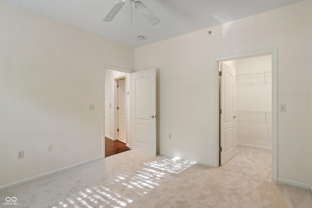 unfurnished bedroom with a spacious closet, carpet flooring, a closet, and baseboards