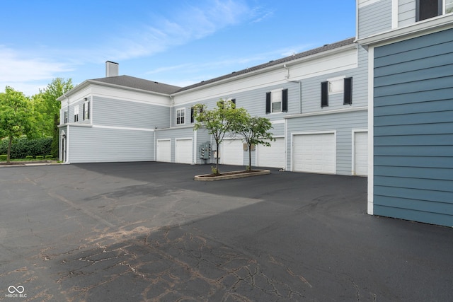 view of front of home featuring a chimney and asphalt driveway