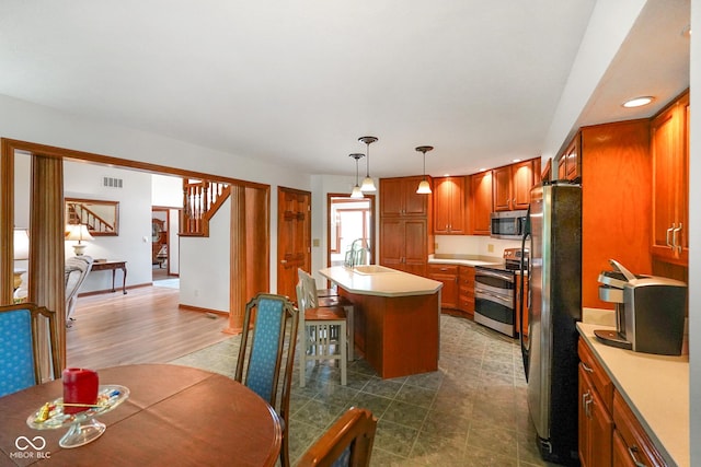 2508 Indian Creek Rd, Trafalgar, IN 46181 - kitchen with appliances with stainless steel finishes, light countertops, brown cabinetry, a center island with sink, and recessed lighting