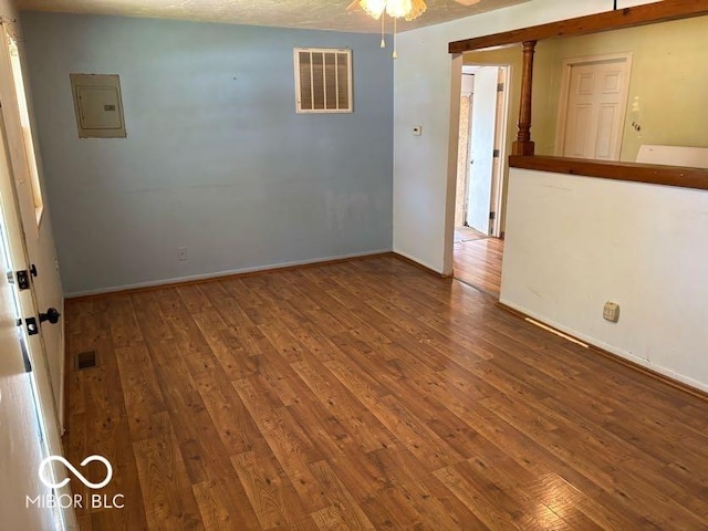 spare room with electric panel, wood-type flooring, ceiling fan, and baseboards