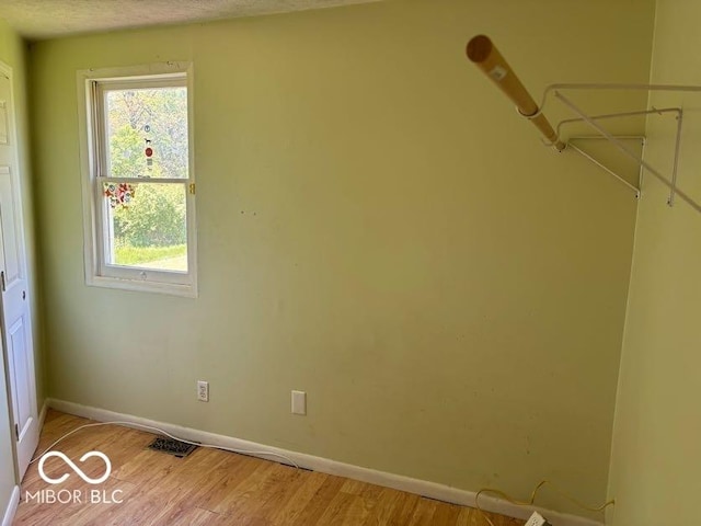 empty room with healthy amount of natural light, baseboards, and light wood finished floors