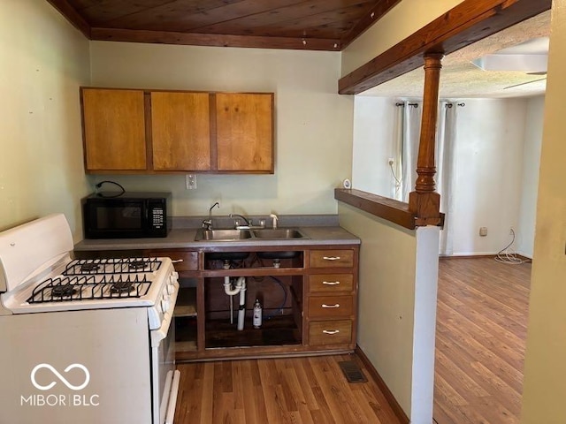 kitchen featuring black microwave, white gas range, a sink, brown cabinets, and wood ceiling