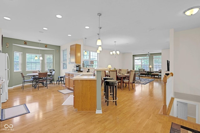 575 Dylan Dr, Avon, IN 46123 - kitchen with a kitchen bar, a sink, a peninsula, light wood-style flooring, and light countertops