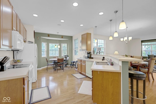 575 Dylan Dr, Avon, IN 46123 - kitchen featuring white appliances, a sink, a breakfast bar area, a peninsula, and light wood finished floors